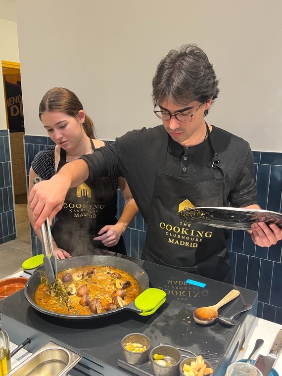 A cooking class, finishing a pan of paella.