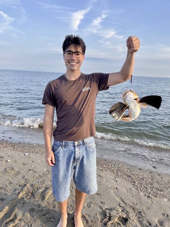 Holding up a fish on a beach.
